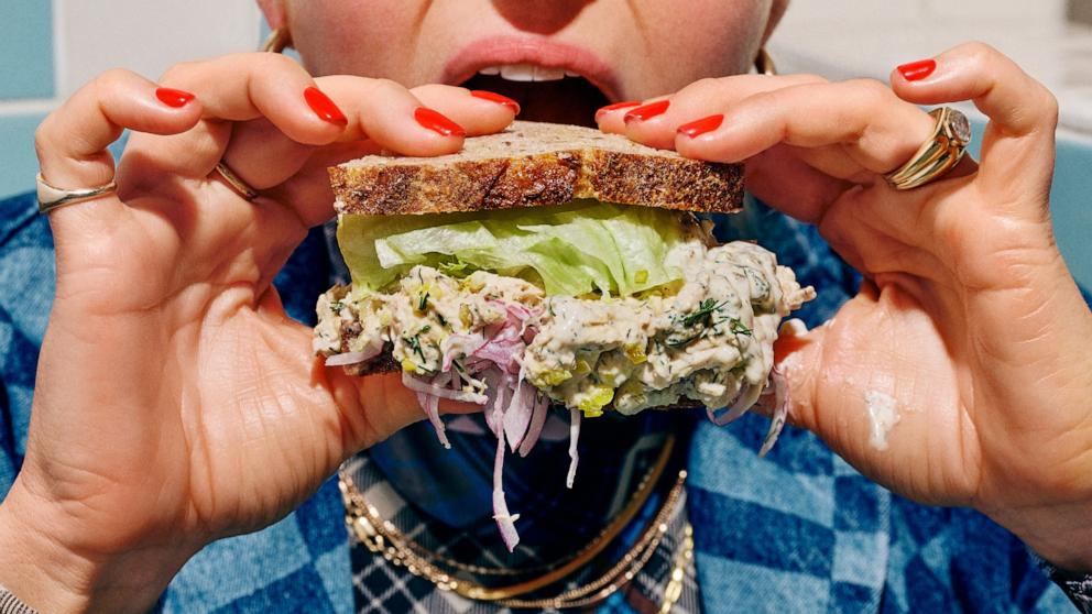 PHOTO: Molly Baz eating a tuna sandwich with dill pickle Ayoh.