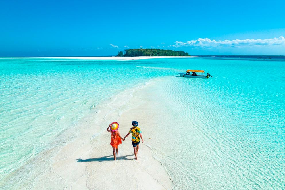 PHOTO: Overhead view of man and woman holding hands on idyllic beach