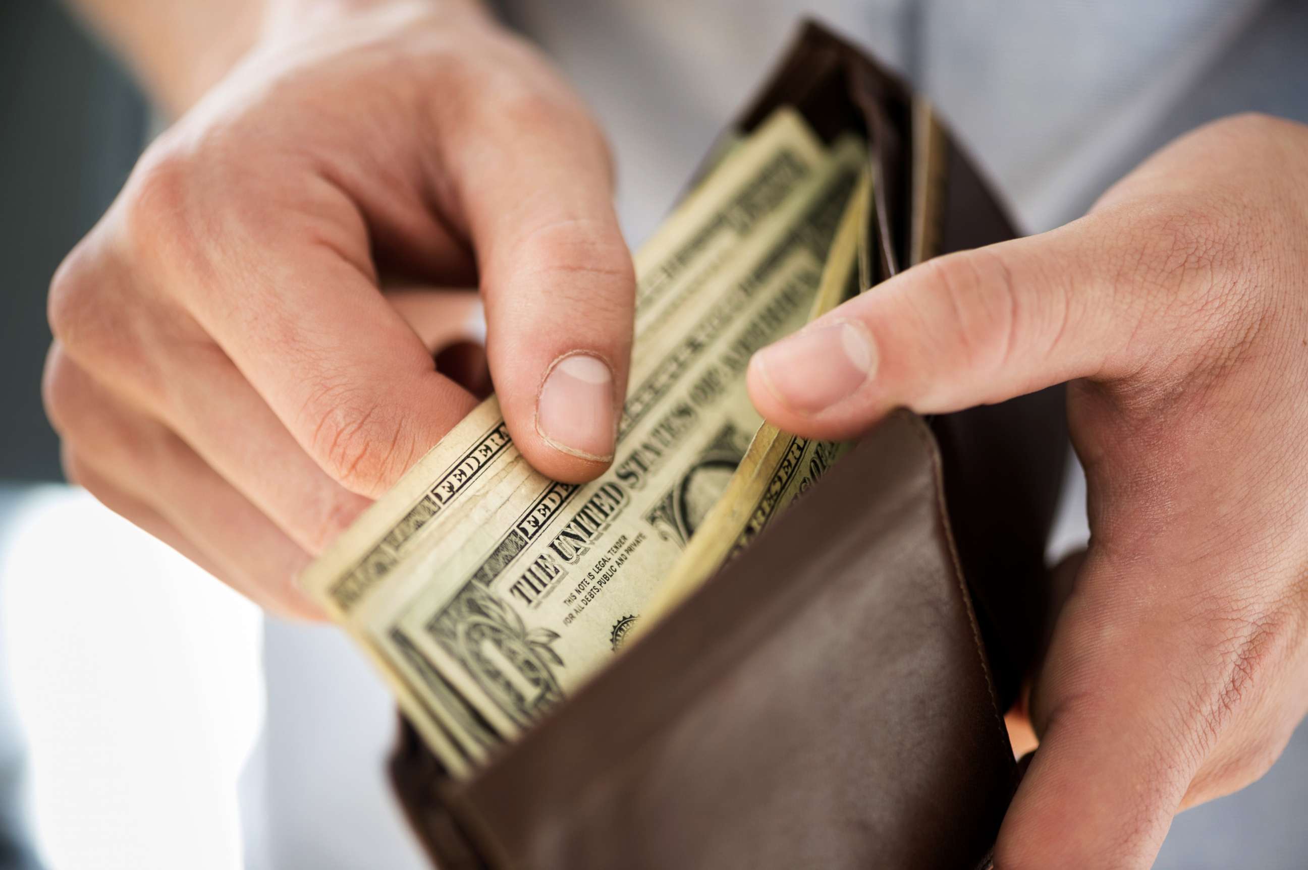 PHOTO: A person looks at the money in their wallet in an undated stock photo.