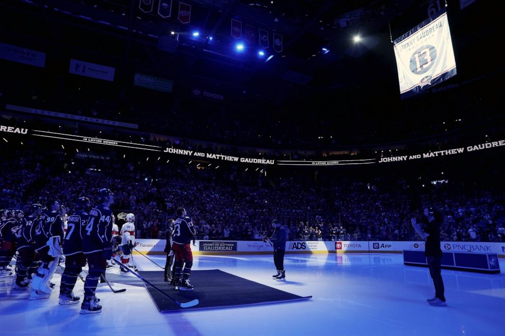 PHOTO: Sean Monahan (23) of the Columbus Blue Jackets stands in front of his teammates and the Florida Panthers as a banner is raised in remembrance of Johnny Gaudreau at Nationwide Arena in Columbus, Ohio, Oct. 15, 2024.