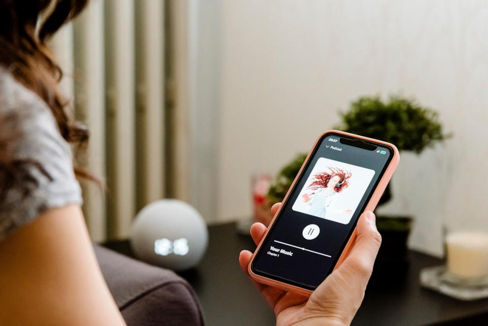 PHOTO: woman choosing music on her cell phone to listen to on her smart speaker