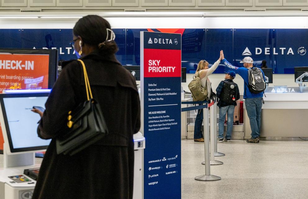 PHOTO: A woman checks in for her flight as a family celebrates at a Delta Airlines check-in counter at George Bush Intercontinental Airport on Dec. 27, 2022 in Houston, Texas. 