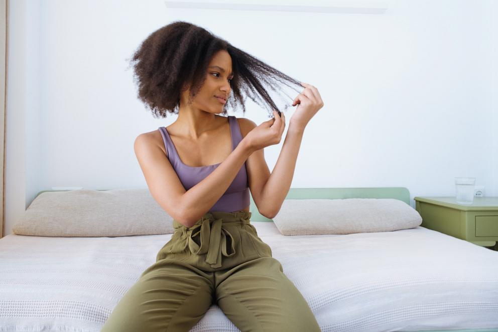 PHOTO: A frustrated woman holding strands of hair with her hands. 