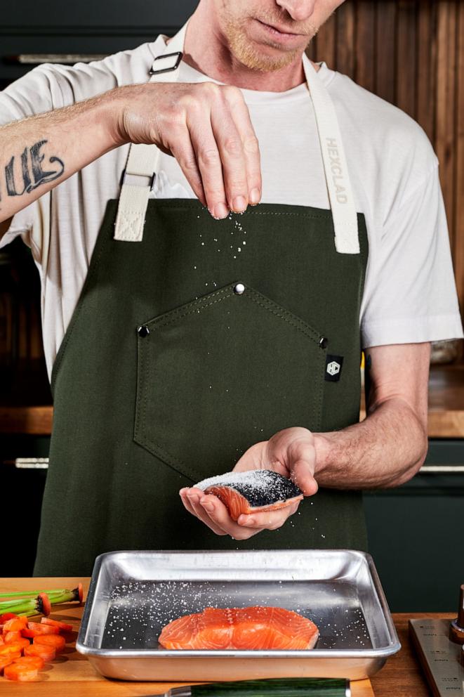 PHOTO: A chef seasons a piece of fish wearing the new Eco Modern Apron from HexClad.