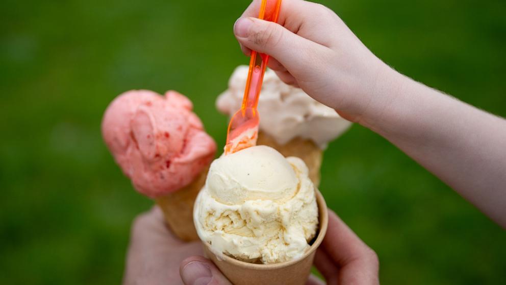 A toddler eats ice cream from a cone in summer temperatures. 