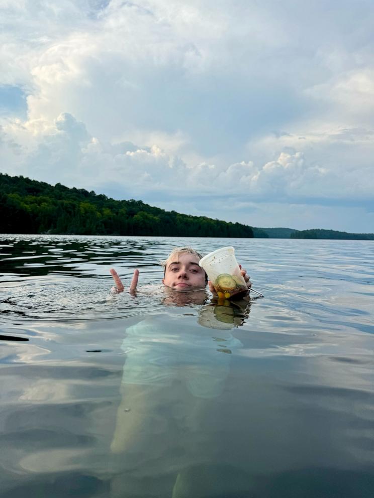 PHOTO: Logan Moffitt holds a deli container of his sliced cucumber salad in the water.