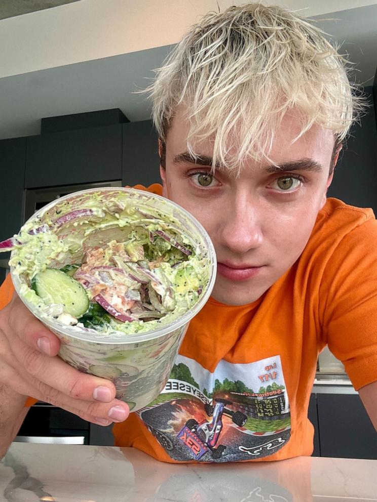 PHOTO: Logan Moffitt holds a deli container of his sliced cucumber salad in his kitchen.