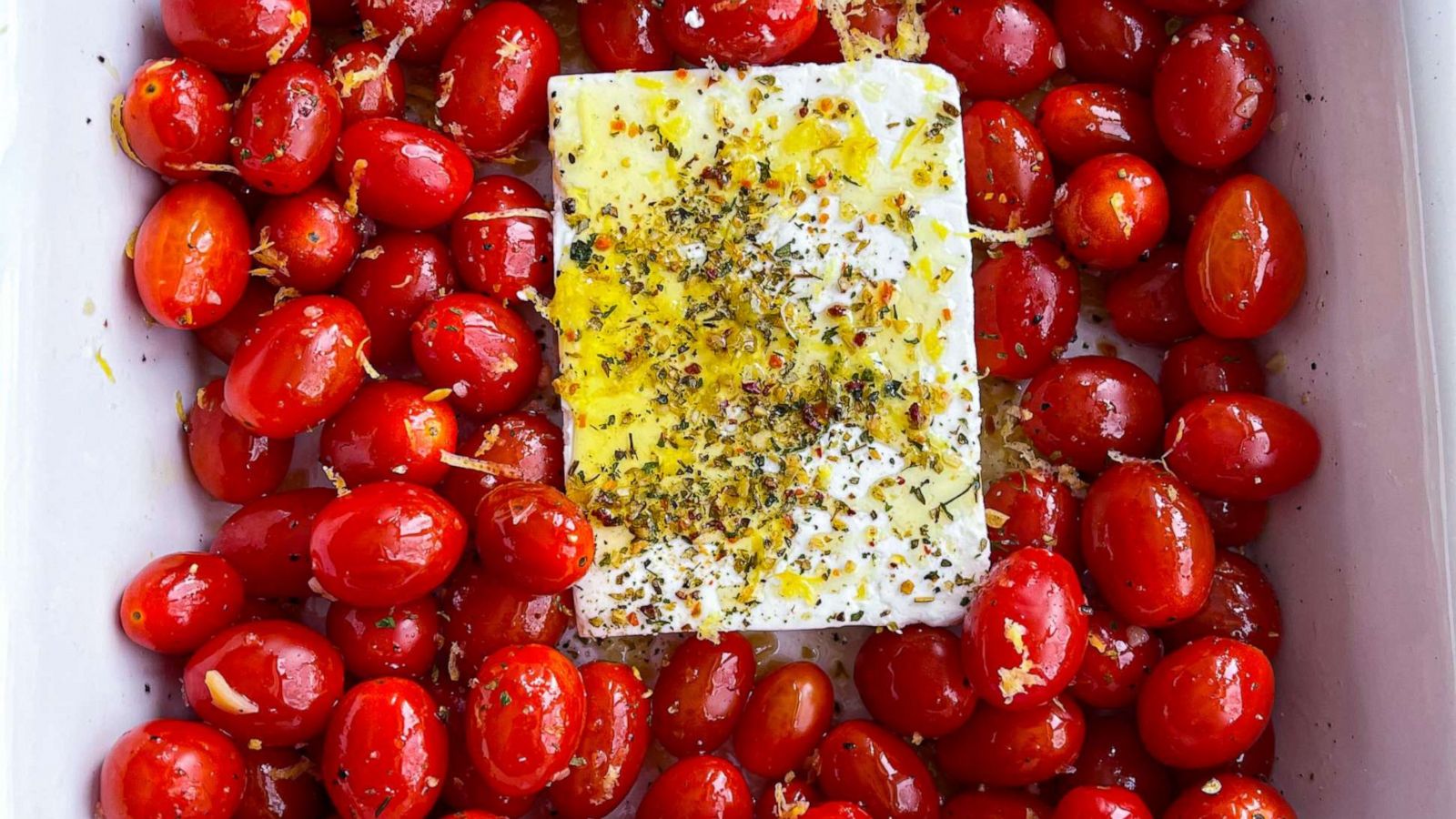 PHOTO: Cherry tomatoes with a block of feta cheese, herbs, garlic and olive oil prepared in a baking dish.