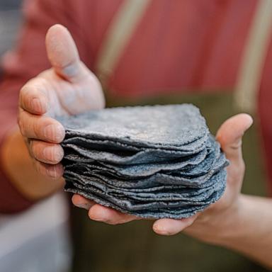 PHOTO: Milpa chef and owner DJ Flores holds a stack of fresh blue corn tortillas.