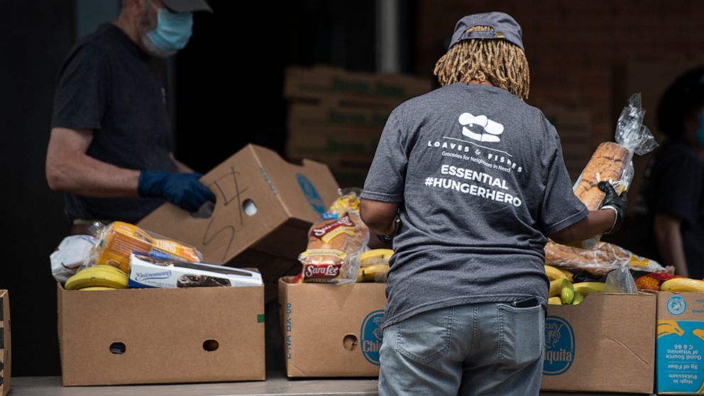 PHOTO: Loaves & Fishes volunteers pack boxes with food for donation.