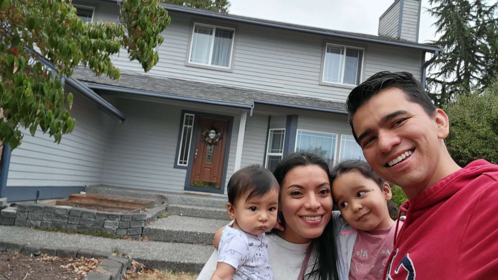 PHOTO: Kenneth and Adi Martinez and their two children pose in front of their Seattle-area home, where they are hosting a family of Afghan refugees.