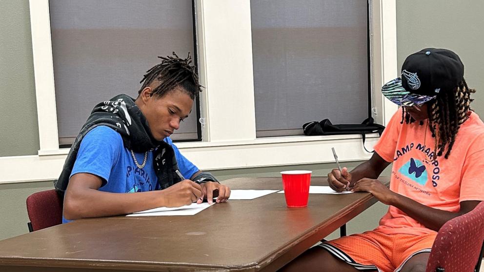 PHOTO: Jeremiah, left, and Zy, both campers at Camp Mariposa, write letters to addiction at the camp.