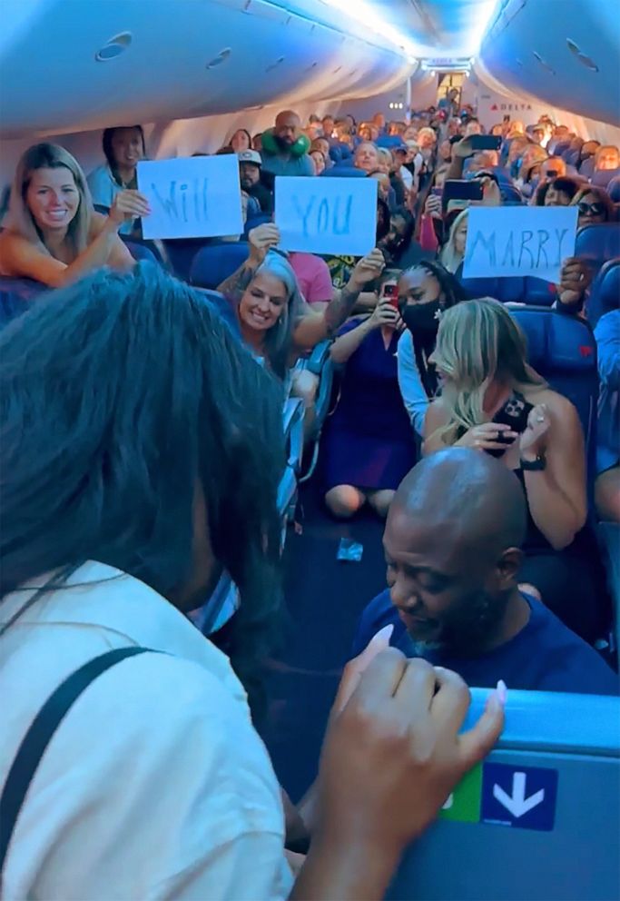 PHOTO: While Brinkley got down on one knee, other flight passengers teamed up to hold up signs that read, "Will you marry me?"