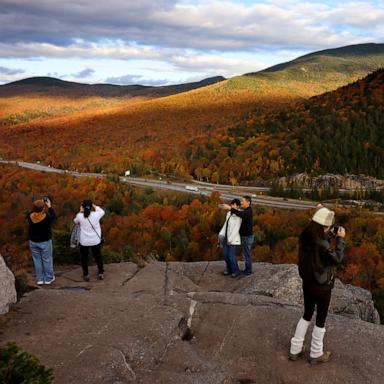 PHOTO: People take photos of the fall foliage as they look out from the top of Artist's Bluff in Franconia Notch State Park, N.H., Oct. 8, 2024.