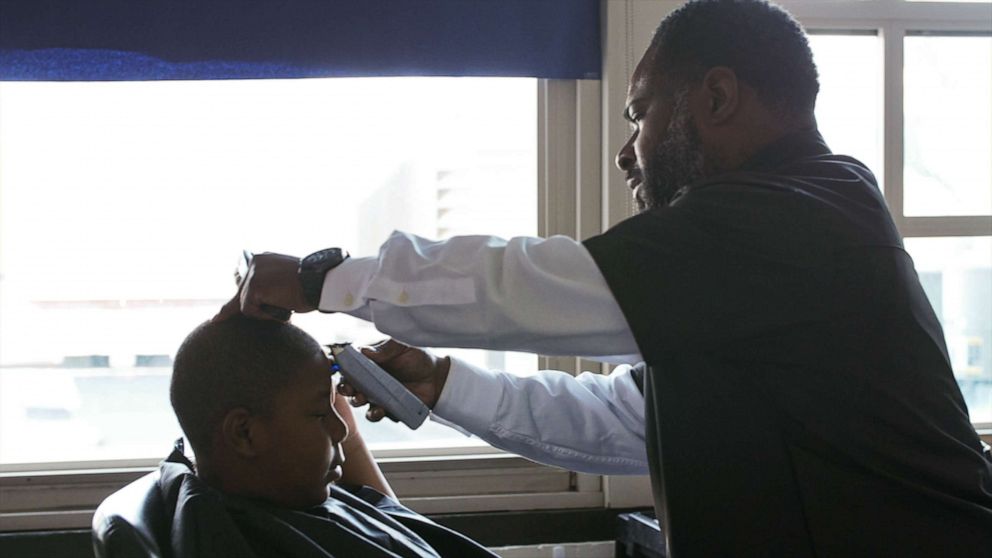PHOTO: Principal Dr. Terrance Newton cutting a student's hair at the barbershop he opened at Warner Elementary School.