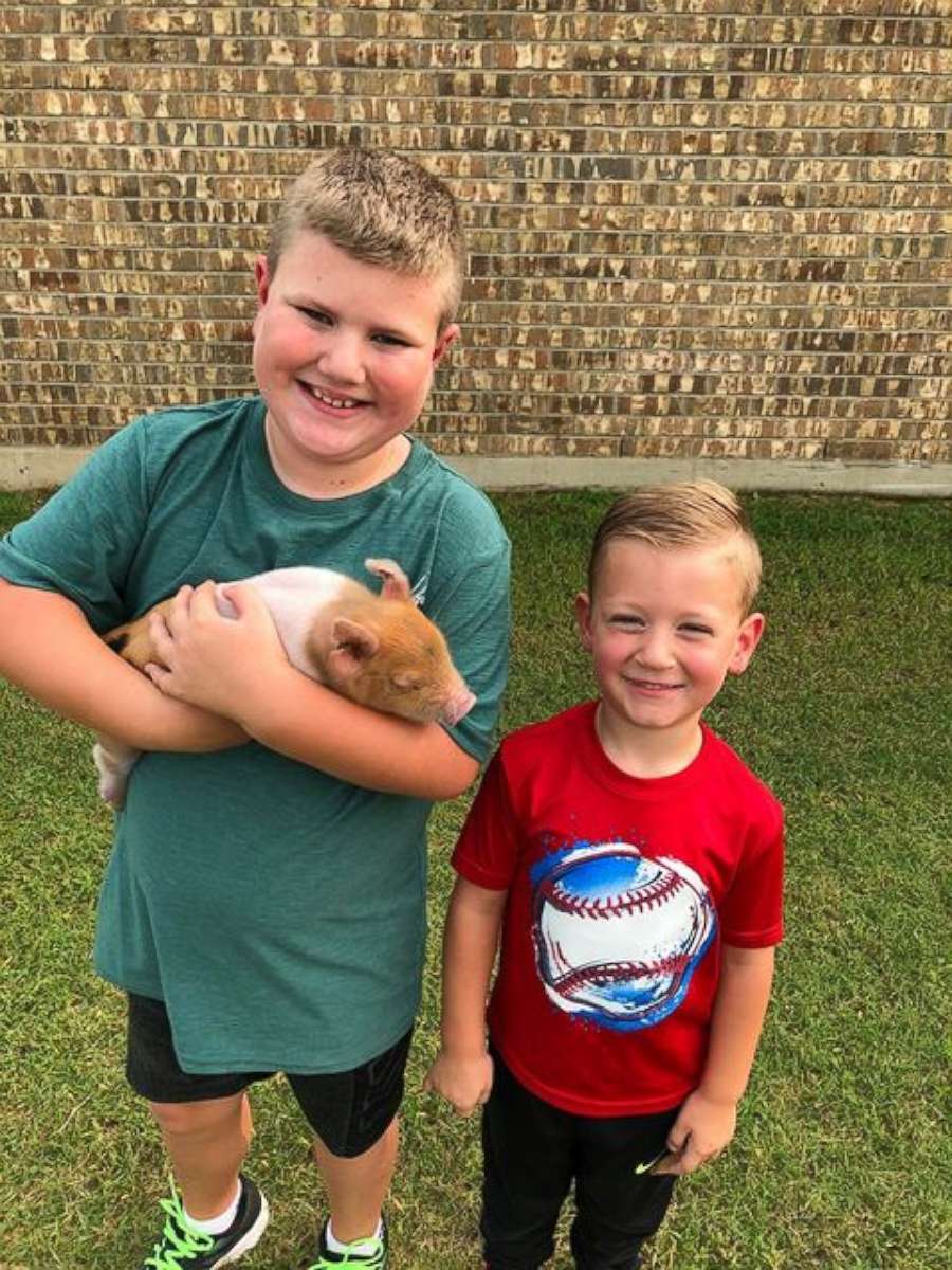 PHOTO: Jase (left) and Boden (right) pose with piglet named Dynamite.