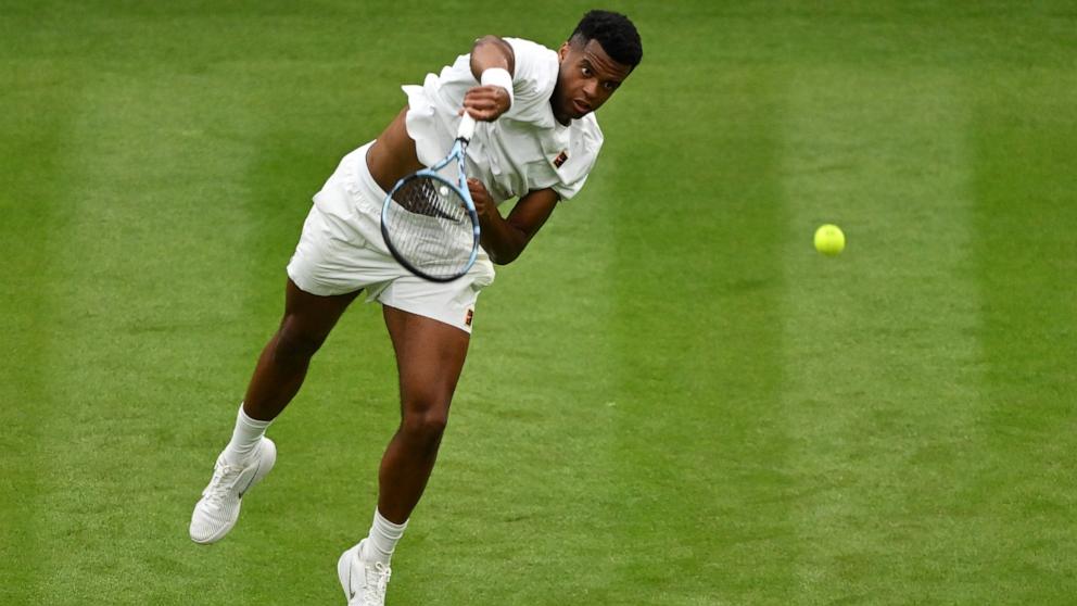 PHOTO: Giovanni Mpetshi Perricard of France serves against Taylor Fritz of U.S. during their Gentlemen's Singles first round Wimbledon match, June 30, 2025 in London.