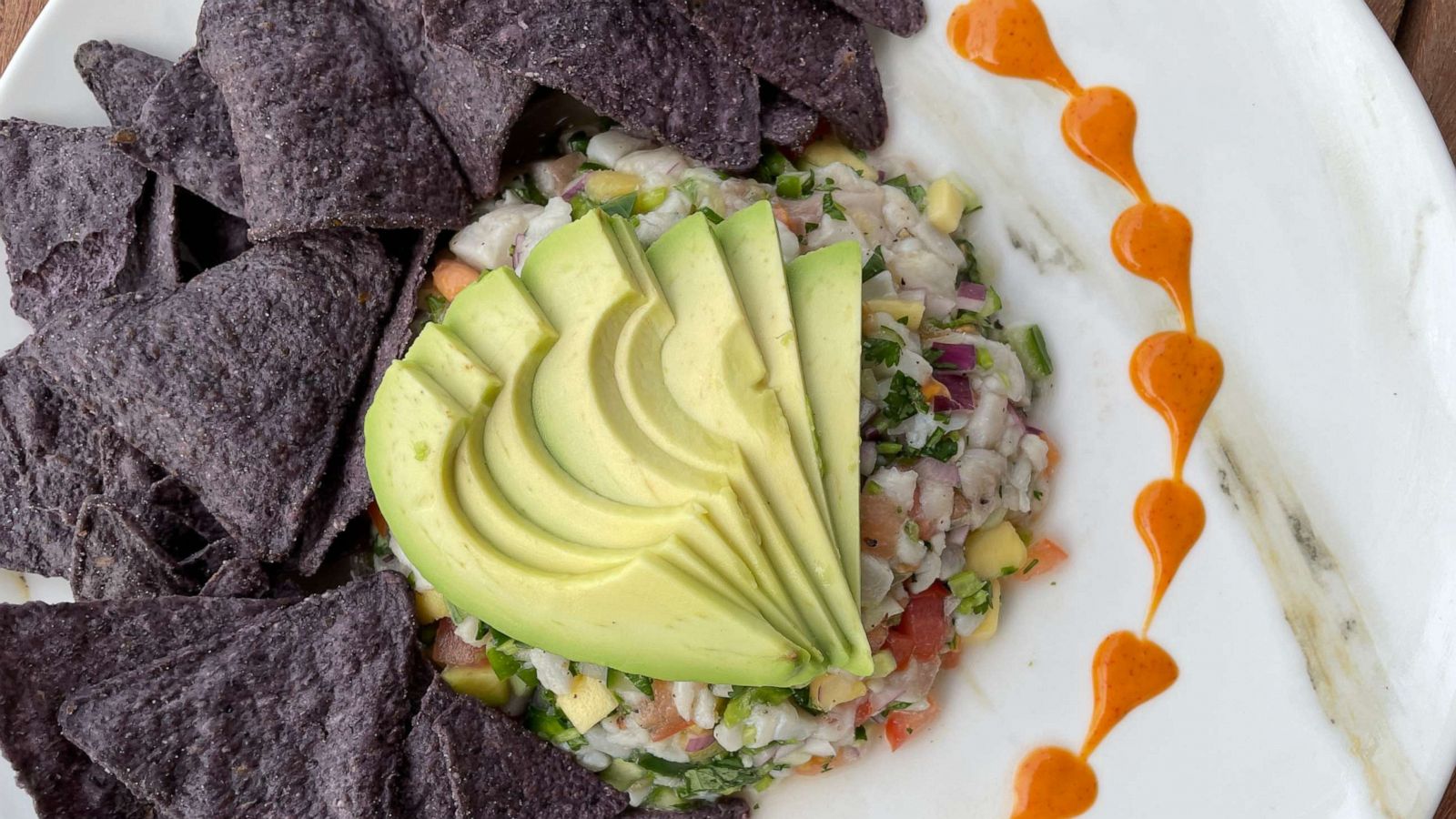 PHOTO: A plate of fish ceviche with avocado and blue corn tortillas.