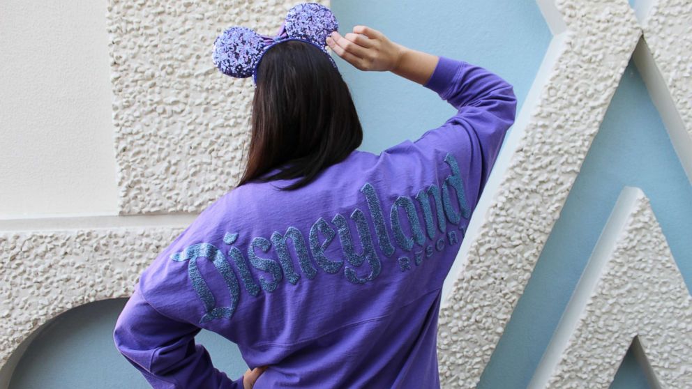 The Potion Purple Spirit Jersey features long sleeves and a shimmery resort logo with a “D” icon on the front while the back displays Disneyland Resort in its signature font.