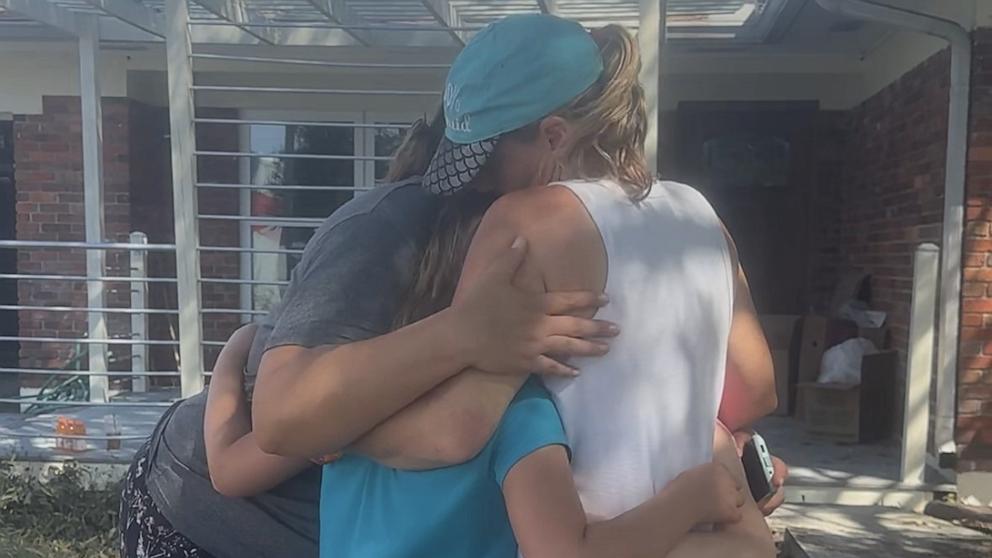 PHOTO: Sarah Spicer and her daughter Blakely hug neighbors after Hurricane Helene flooded parts of their neighborhood.