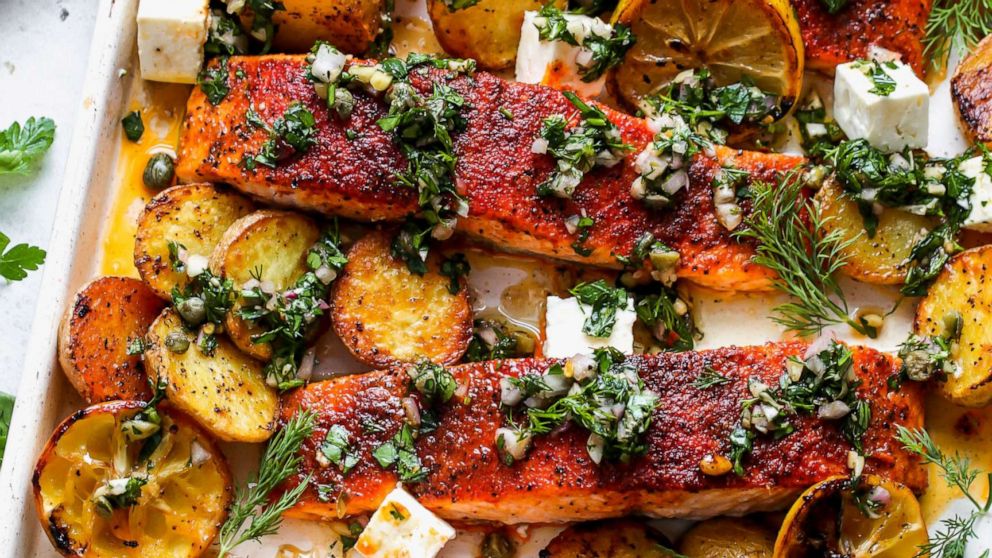 PHOTO: A tray of sheet pan salmon with potatoes and lemon, topped with caper chimichurri.