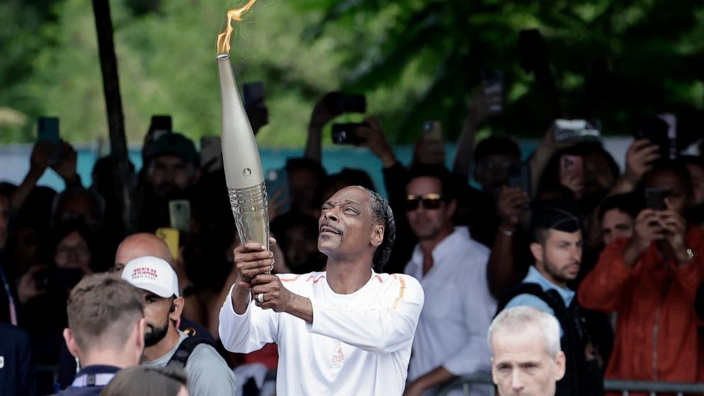 PHOTO: Snoop Dogg holds the torch as part of the 2024 Paris Olympic Games Torch Relay, in Saint-Denis, July 26, 2024.