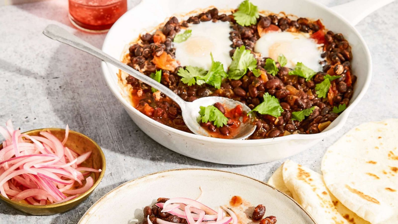 PHOTO: Spiced beans and eggs plated with pickled red onions.