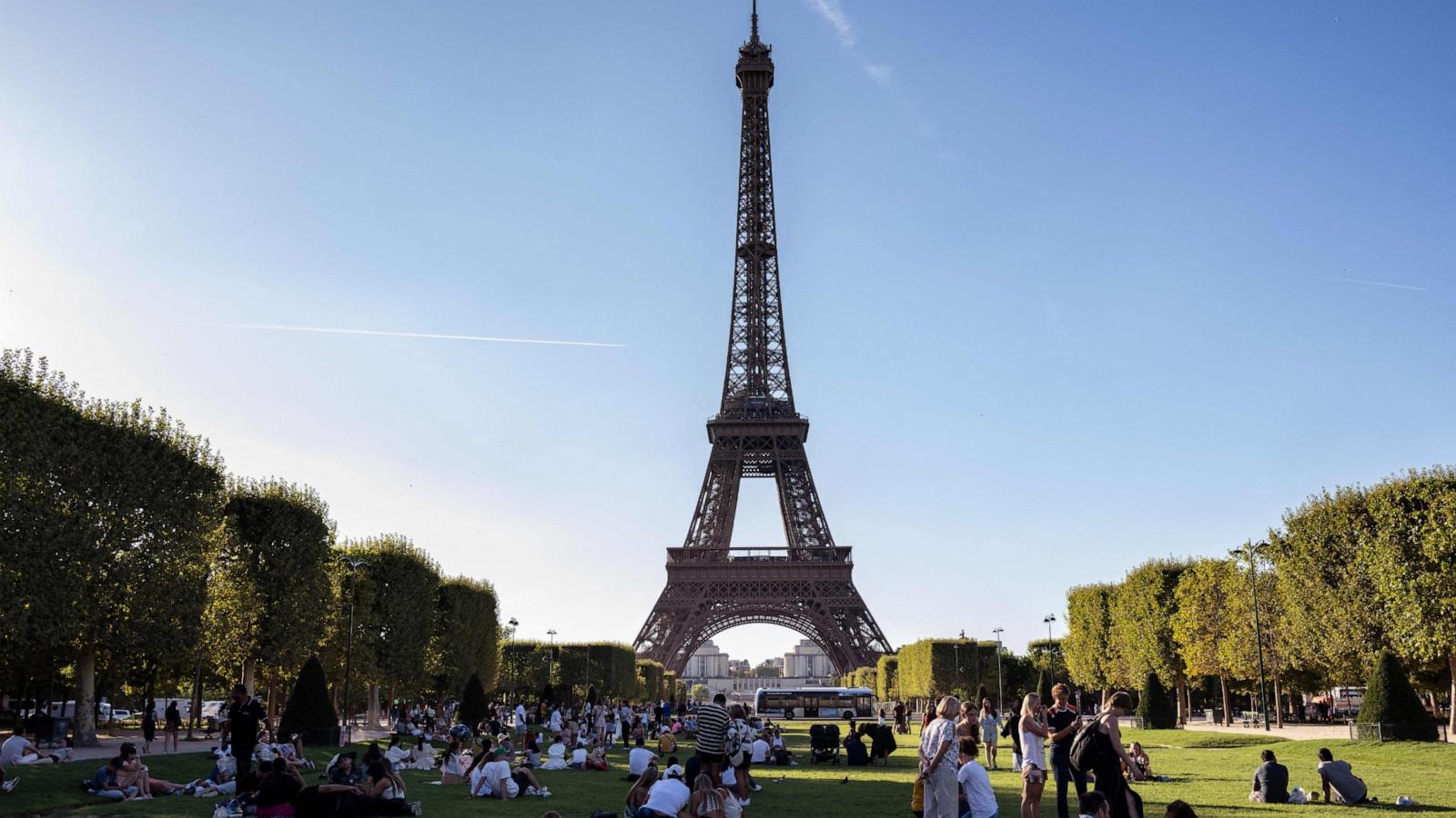 PHOTO: Tourists and Parisians sit in the Champ de Mars garden in front of the Eiffel Tower in Paris, Aug. 21, 2023.