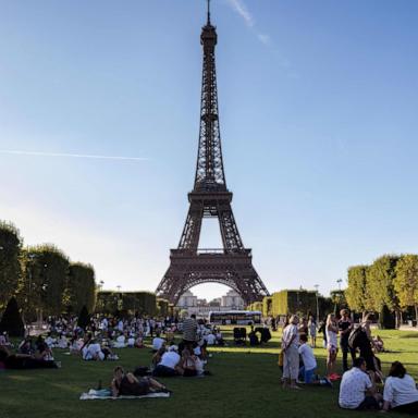 PHOTO: Tourists and Parisians sit in the Champ de Mars garden in front of the Eiffel Tower in Paris, Aug. 21, 2023. 