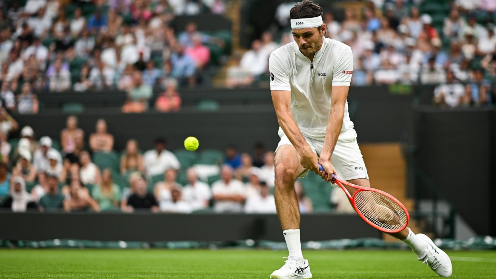 Taylor Fritz returns a shot from unranked French tennis player Giovanni Mpetshi Perricard during the Men's Singles First Round match on day one of The Championships Wimbledon 2025.