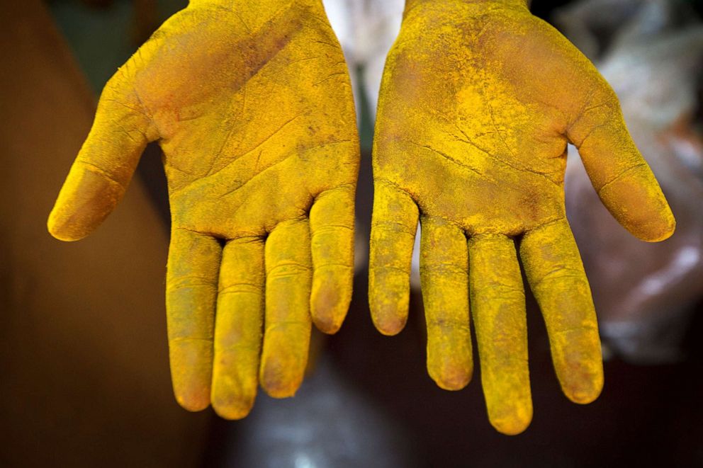 PHOTO: A worker is covered with turmeric powder at a spice shop in Mumbai on September 5, 2012. 