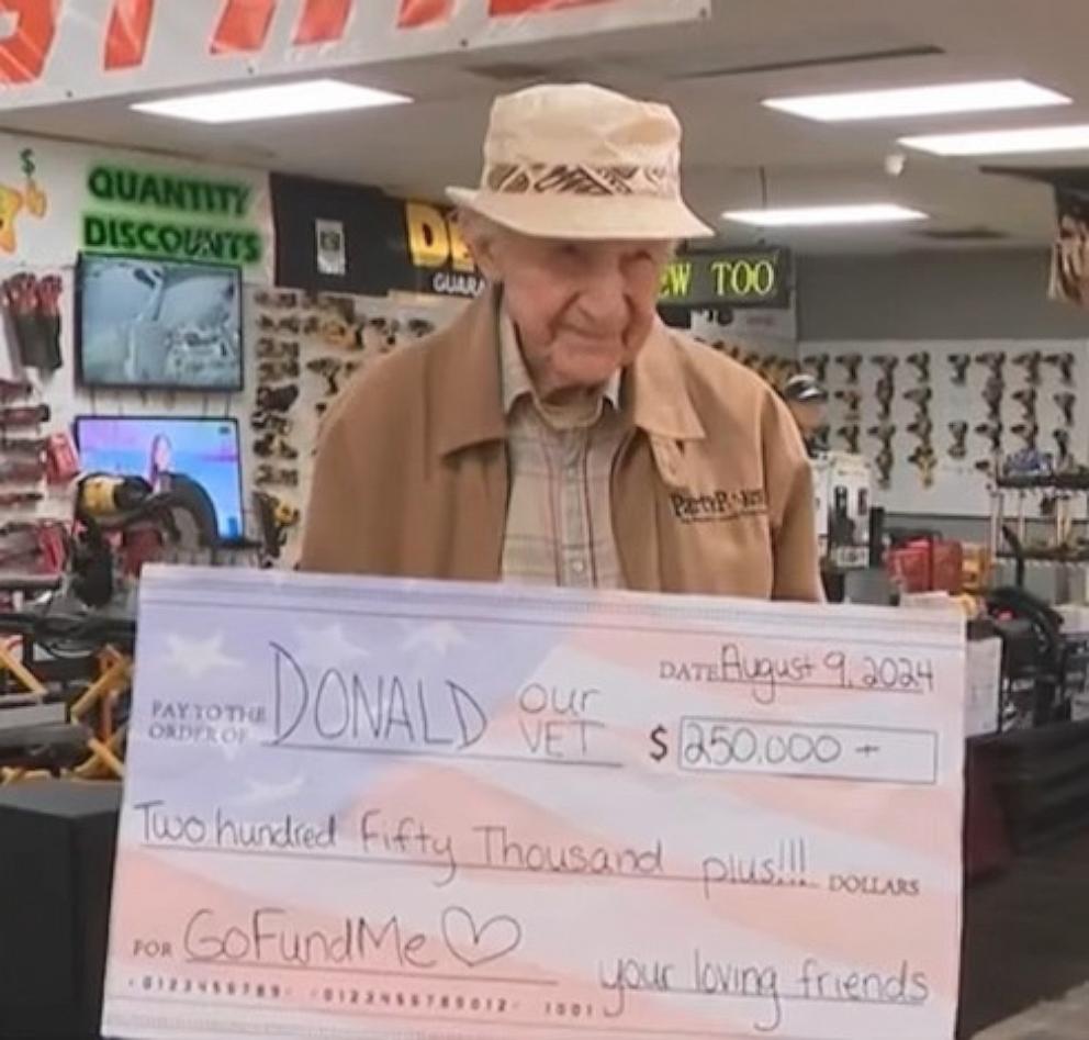 PHOTO: Donald holds a check for $250,000. The online fundraiser for him has now reached over $446,000.