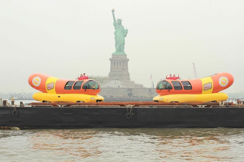 PHOTO: Two of the Wienermobiles in front of the Statue of Liberty.