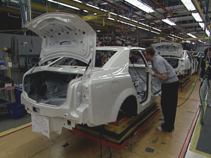 A picture of a car being made on an assembly line.
