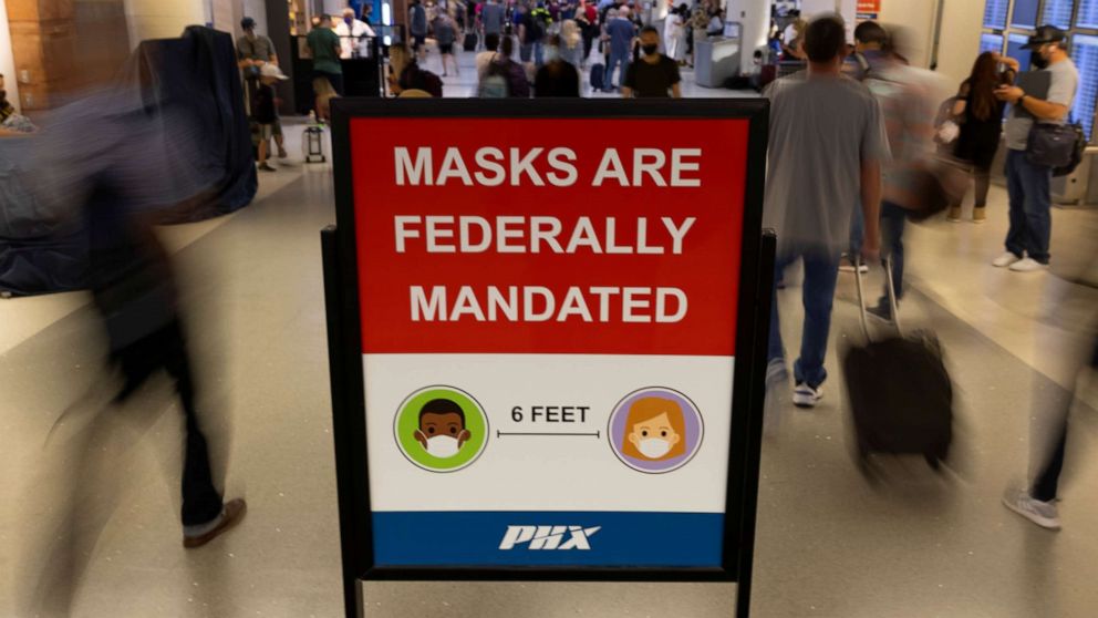 PHOTO: Air travelers make their way past a sign mandating face masks for all during the outbreak of the coronavirus disease (COVID-19) at Phoenix international airport in Phoenix, Arizona, Sept. 24, 2021.