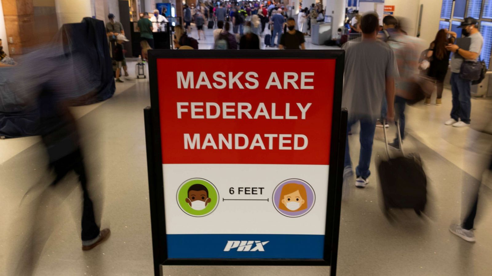 PHOTO: Air travelers make their way past a sign mandating face masks for all during the outbreak of the coronavirus disease (COVID-19) at Phoenix international airport in Phoenix, Arizona, Sept. 24, 2021.