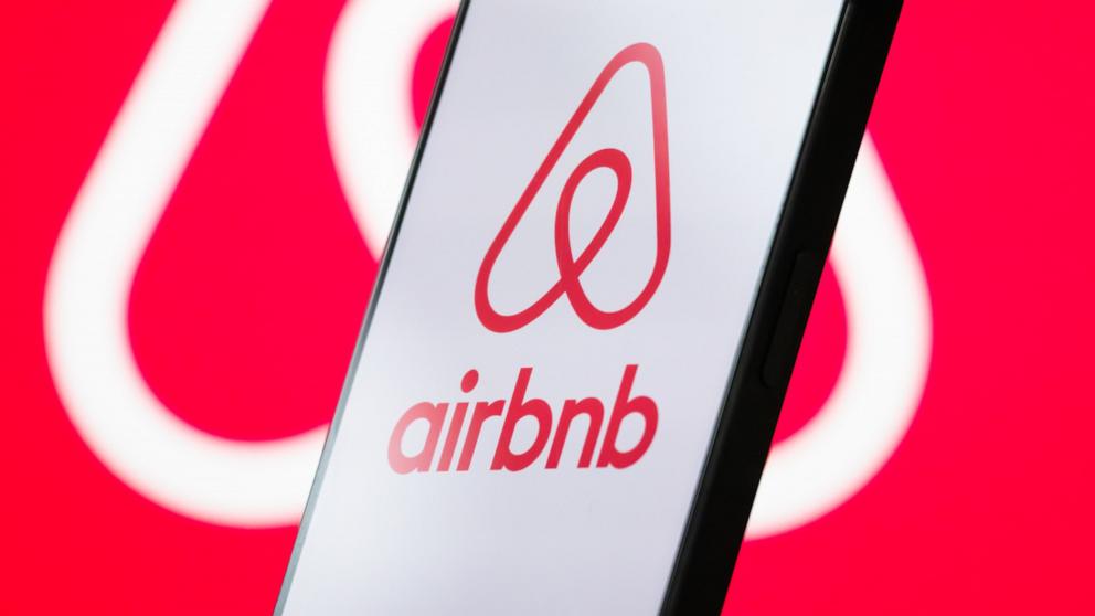 PHOTO: The logo of Airbnb, Inc. is displayed on a smartphone screen, with the company's branding visible in the background.