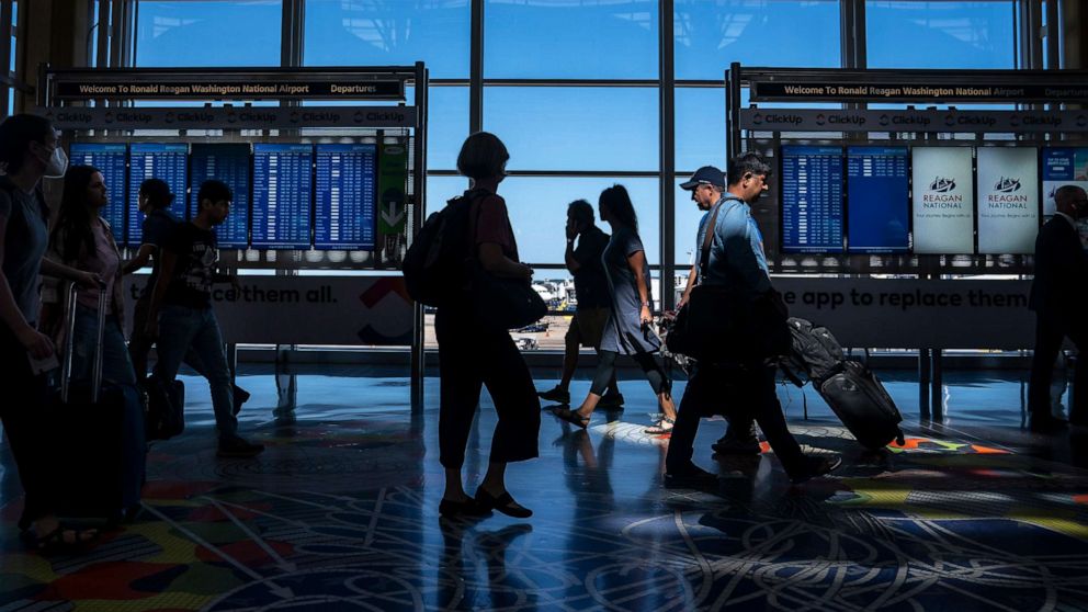 PHOTO: Travelers check their flight status at Ronald Reagan Washington National Airport, July 11, 2022, in Arlington, Va. 