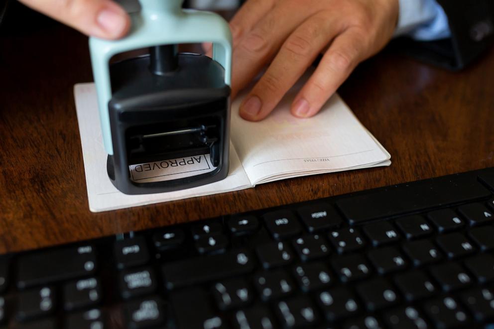 PHOTO: An airport employee stamps a passports of a passenger.