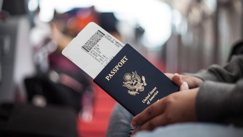 PHOTO: Close Up of a person holding an American Passport at an airport.