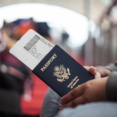 PHOTO: Close Up of a person holding an American Passport at an airport.