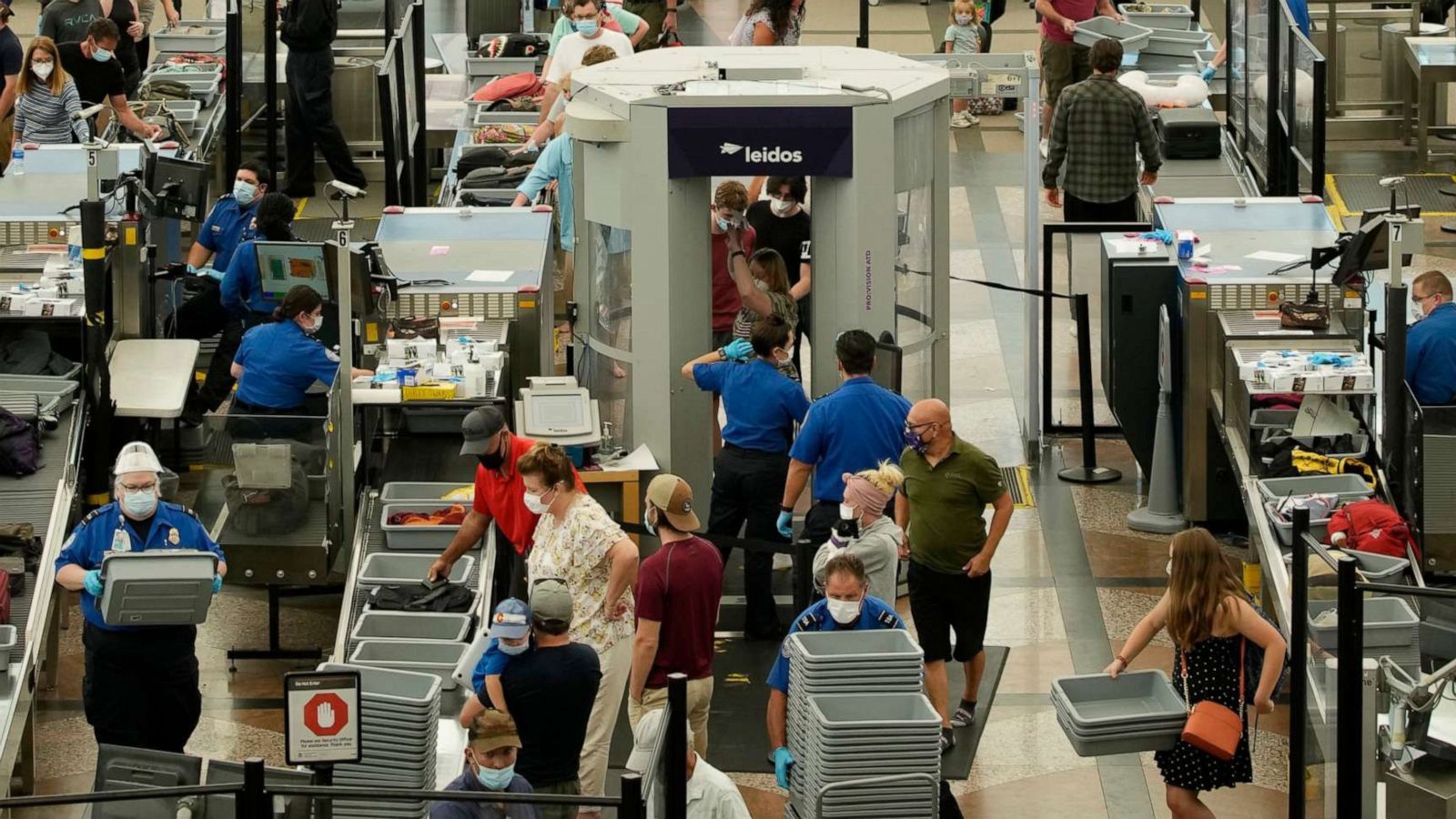 PHOTO: Travelers wear face coverings in the queue for the south security checkpoint in the main terminal of Denver International Airport, Aug. 24, 2021, in Denver.