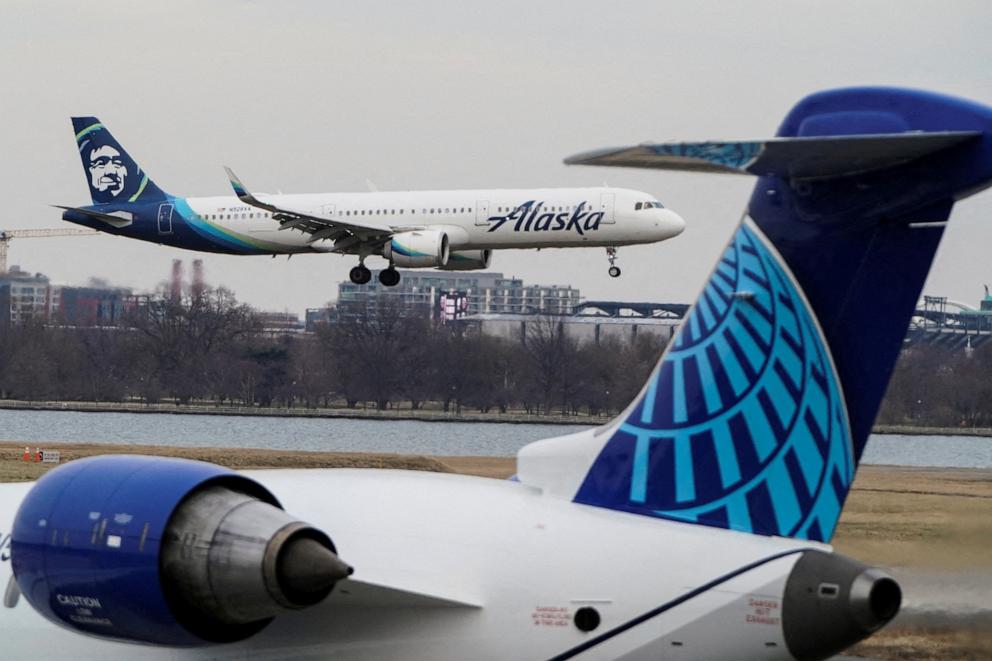 PHOTO: In this Jan. 24, 2022 file photo, an Alaska Airlines aircraft flies past the tail of a United Airlines aircraft as it lands at Reagan National Airport in Arlington, Va.