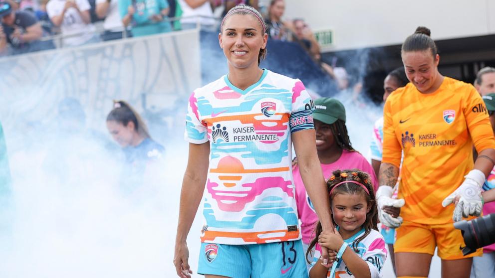 PHOTO: Alex Morgan of San Diego Wave FC walks onto the pitch with her daughter, Charlie before playing the last match of her career Sept. 8, 2024, in San Diego.