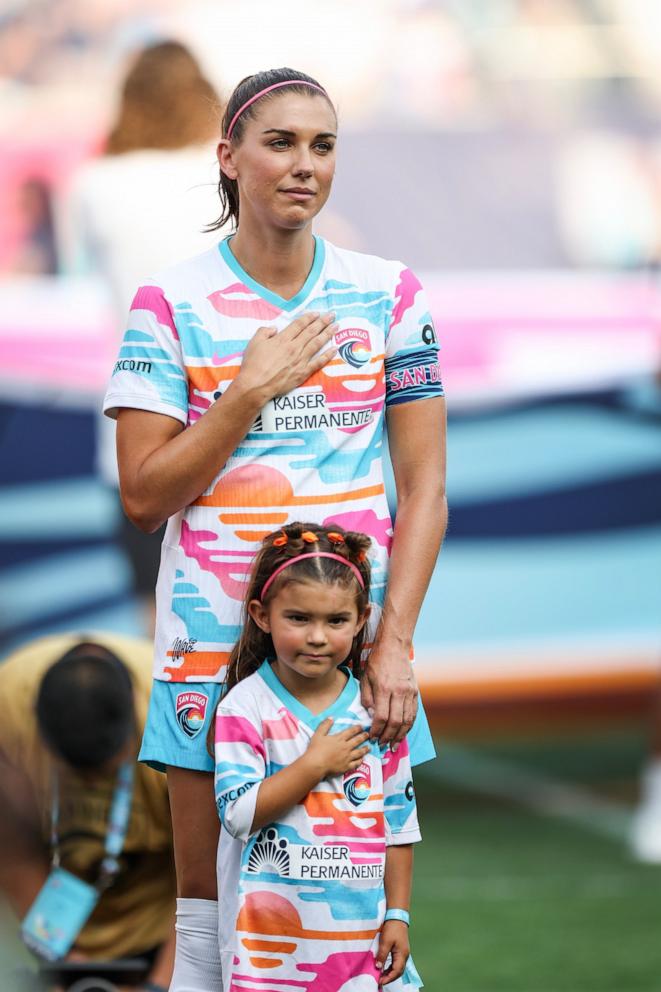 PHOTO: Alex Morgan of San Diego Wave FC stands with her daughter, Charlie during the national anthem before playing the last match of her career Sept. 8, 2024, in San Diego.