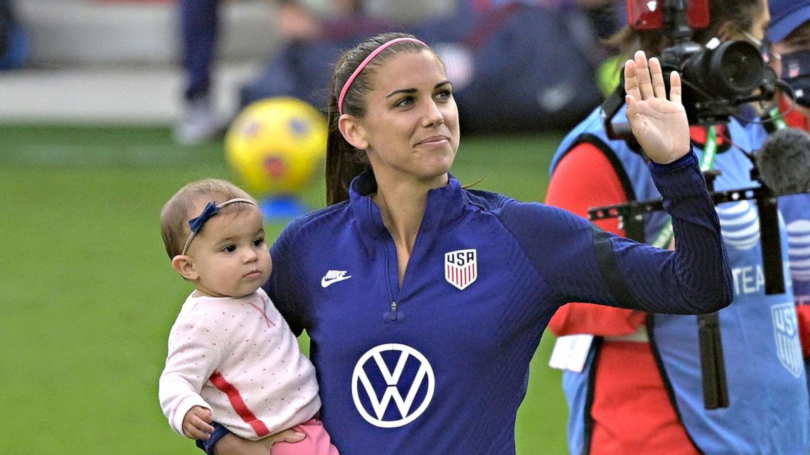 PHOTO: United States forward Alex Morgan waves to fans in the stands while holding her daughter Charlie Elena Carrasco after a SheBelieves Cup women's soccer match against Brazil, Feb. 21, 2021, in Orlando, Fla.