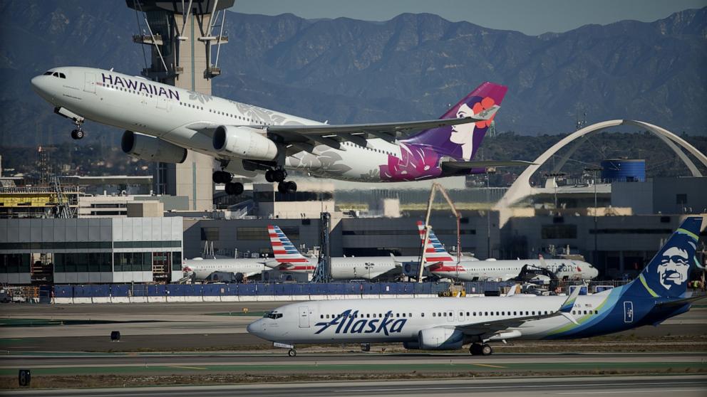 PHOTO: A Hawaiian Airlines airplane takes off near an Alaska Airlines airplane at Los Angeles International Airport (LAX), Dec. 5, 2023, in Los Angeles. 