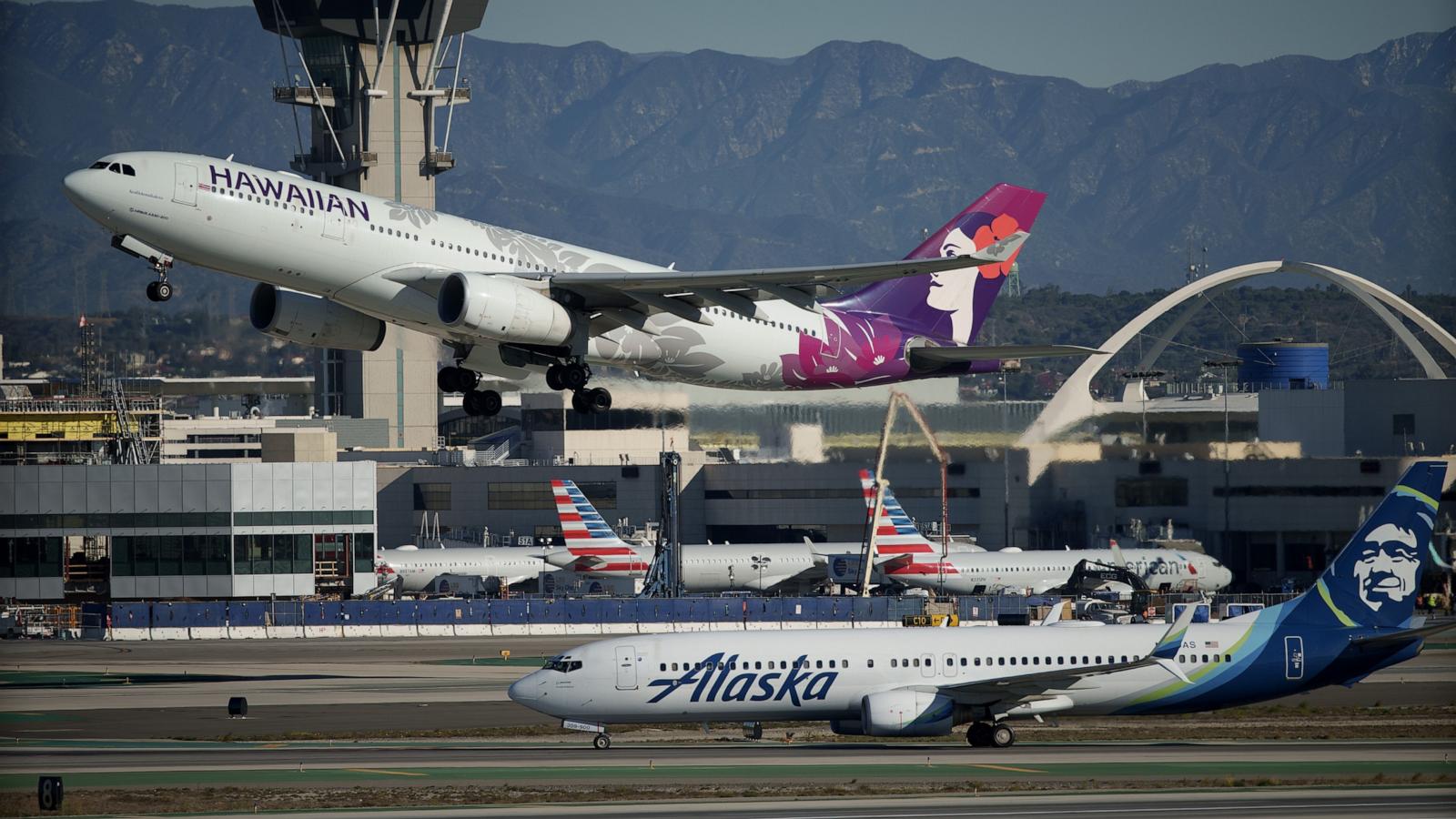 PHOTO: A Hawaiian Airlines airplane takes off near an Alaska Airlines airplane at Los Angeles International Airport (LAX), Dec. 5, 2023, in Los Angeles.