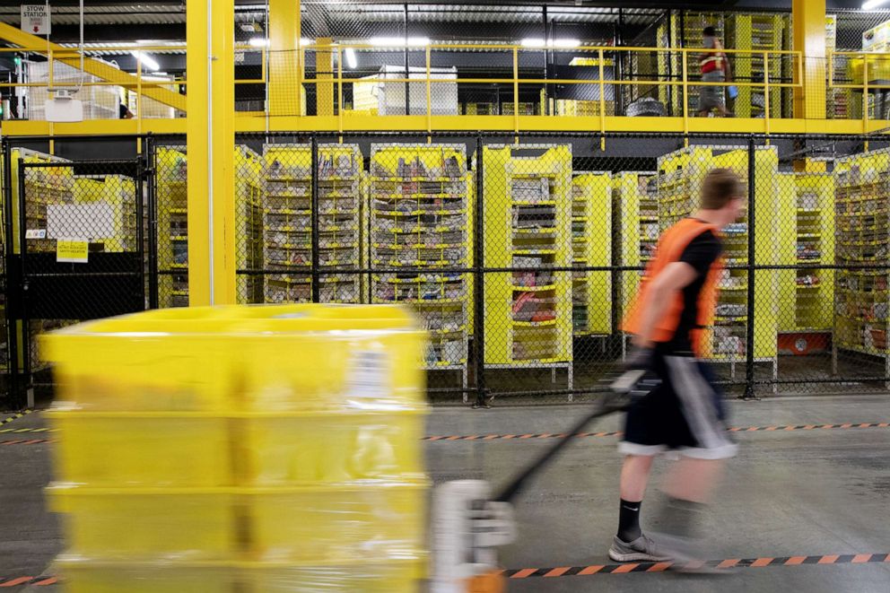 PHOTO: An employee pulls a pallet jack carrying plastic crates past goods in storage units at the Amazon.com Inc. fulfillment center in Robbinsville, N.J., June 7, 2018.