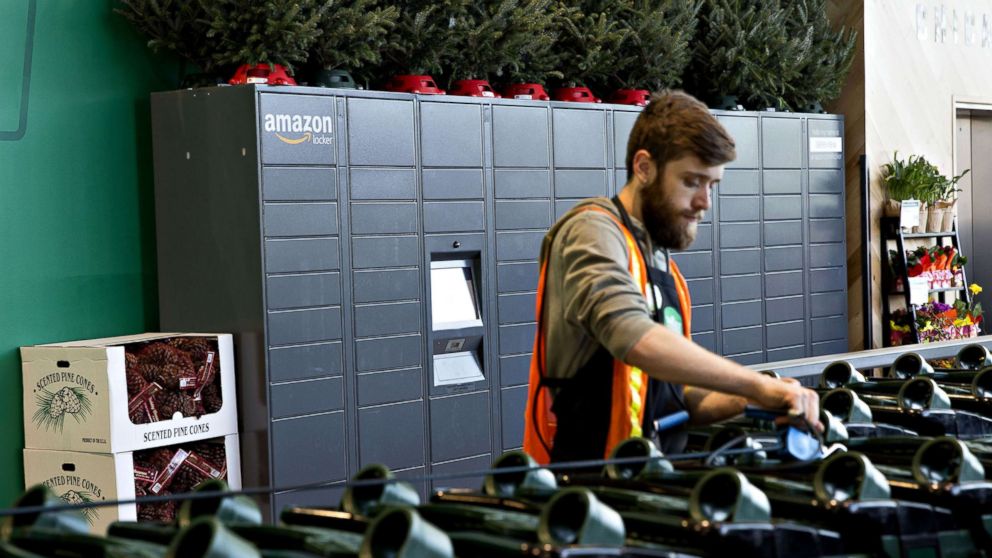 PHOTO: An employee organizes shopping carts in front of a wall of Amazon.com Inc. lockers, a self-service parcel delivery service, inside the Lakeview Whole Foods Market Inc. store in Chicago, Nov. 20, 2017.